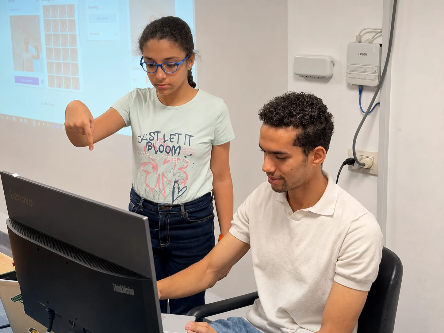 Student discussing an AI task with an instructor at a computer
